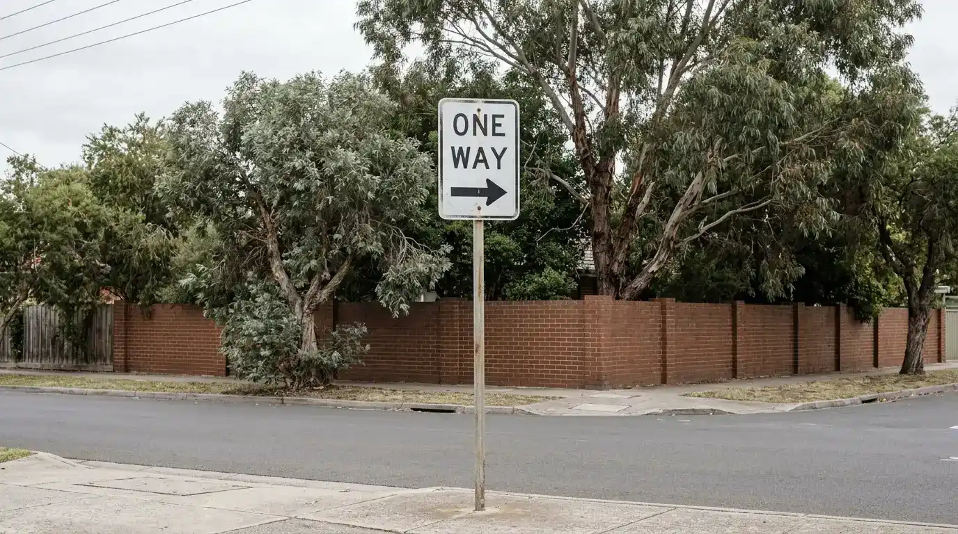 One-way street sign on a quiet suburban corner under overcast light