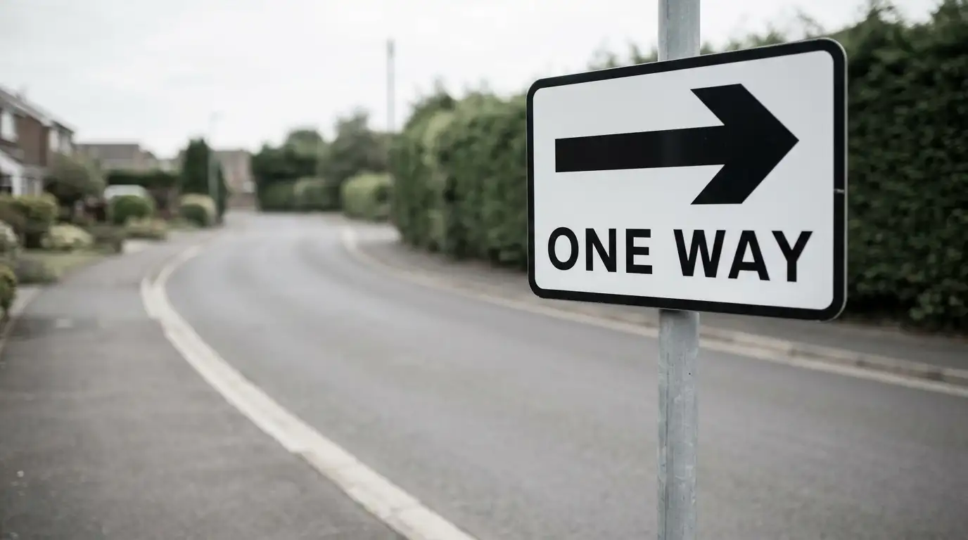 One-way road sign on a quiet street under overcast light